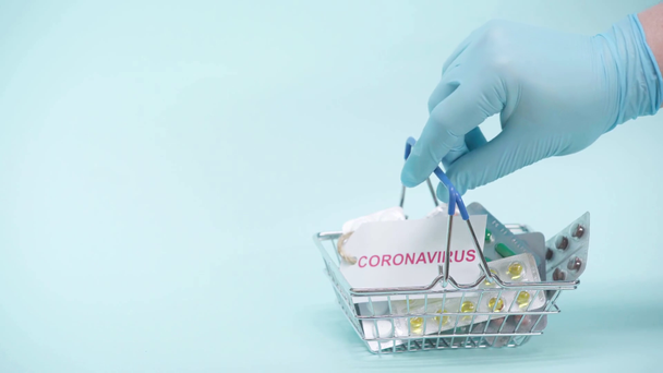 Vista cortada do homem colocando cesta de compras com pílulas no fundo azul - Filmagem, Vídeo