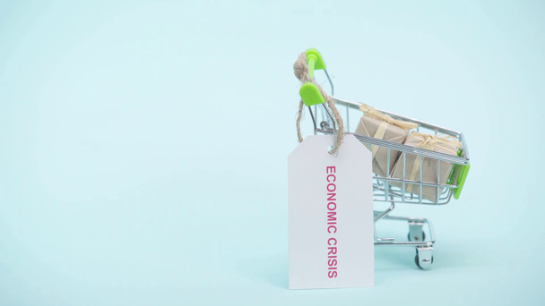 Cropped view of man hanging label on shopping cart on blue background - Footage, Video