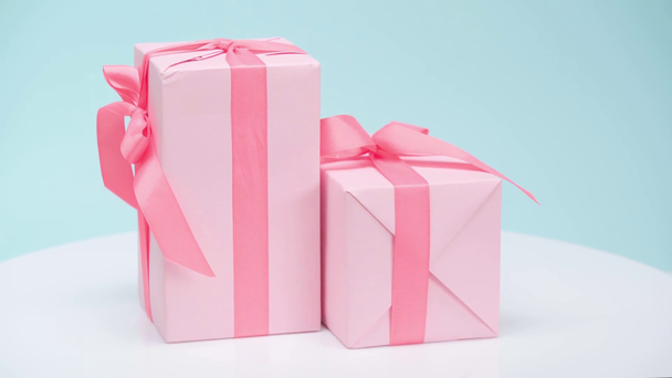 Ροζ κουτιά δώρων που περιστρέφονται σε μπλε φόντο - Πλάνα, βίντεο