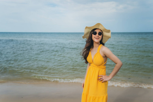 cheerful woman in yellow dress enjoying on the sea beach - Foto, afbeelding