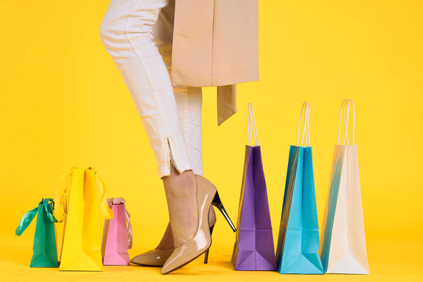 female feet in shoes packs shopping lifestyle yellow isolated background - Photo, image