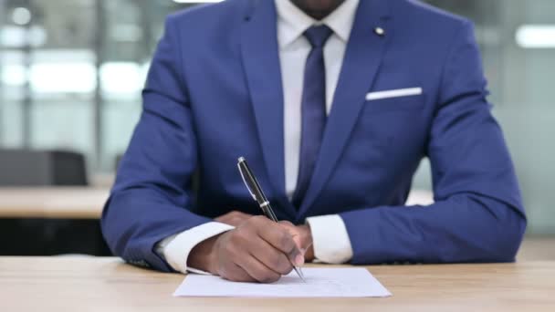 Крупный план африканского бизнесмена, пишущего на бумаге  - Кадры, видео