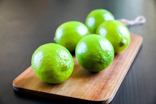 Organic fresh limes on a wooden cutting board - 写真・画像