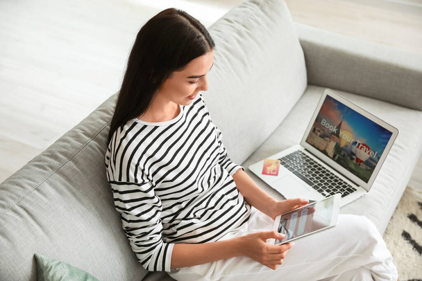 Nainen, jolla on tabletti tietokoneen varaus lippuja verkossa kotona - Valokuva, kuva