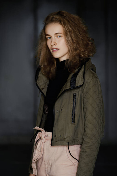 Low key portrait of a student girl in jacket, sweater and trousers - Zdjęcie, obraz