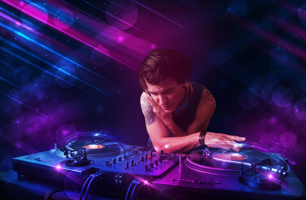 Jovem DJ tocando em toca-discos com efeitos de luz colorida
 - Foto, Imagem