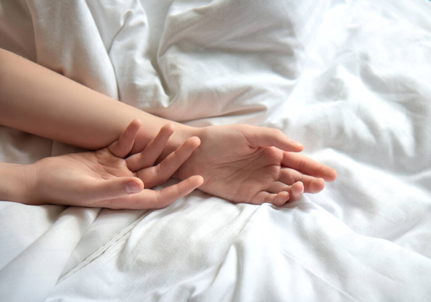 Female hands on white bedding - 写真・画像