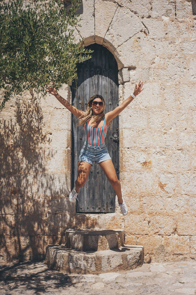 A vertical shot of a cheerful Hispanic female jumping on the Peniscola castle in Spain - Valokuva, kuva