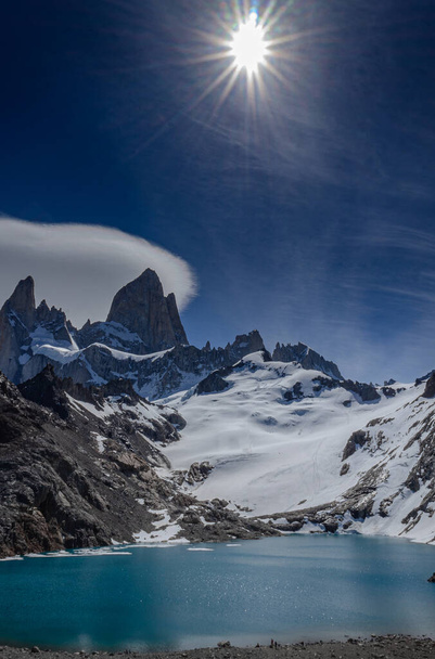 Portrait image of mount Fitz Roy covered in snow with a bright sunshine above. glacial lake in the foreground. El Chalten, Argentina, Patagonia. - Zdjęcie, obraz