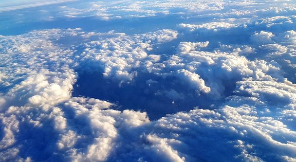 A beautiful scenery of the earth and white fluffy clouds seen from a plane - Foto, imagen