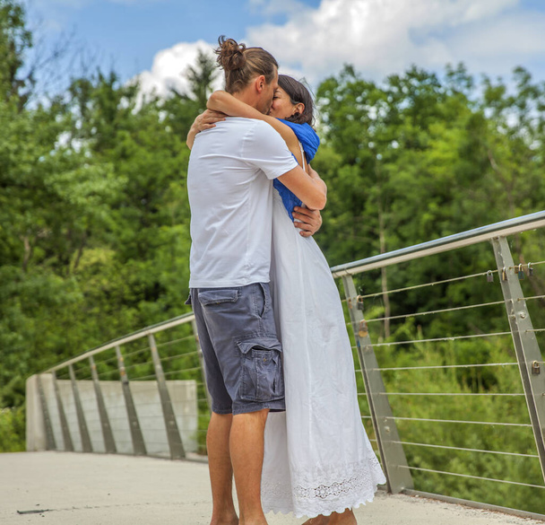 A young couple kissing on background of a bridge - Foto, Imagen
