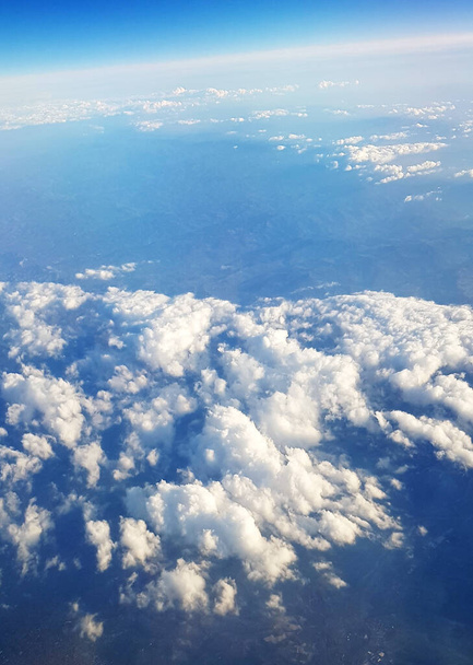 A beautiful scenery of the earth and white fluffy clouds seen from a plane - Fotoğraf, Görsel