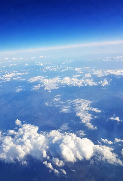 A beautiful scenery of the earth and white fluffy clouds seen from a plane - Фото, зображення