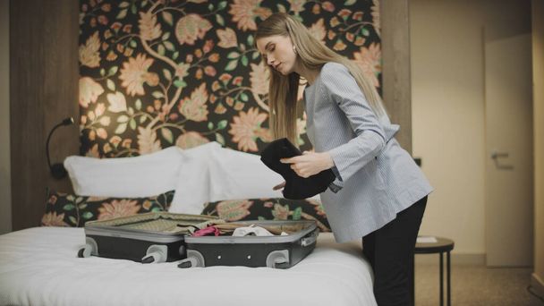 Ładna kobieta otwiera bagaż w pokoju hotelowym. Atrakcyjna kobieta rozpakowująca walizkę - Zdjęcie, obraz