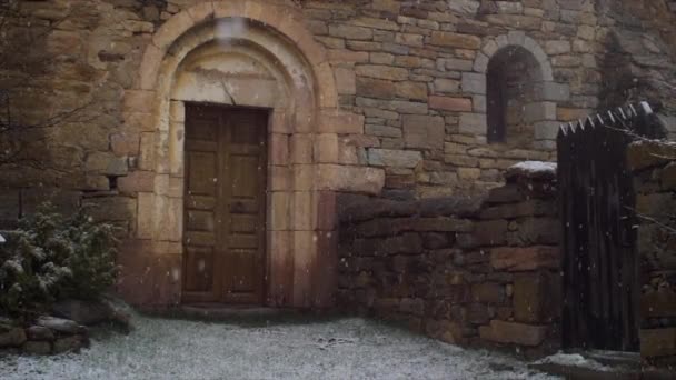 Kış zamanı eski bir ortaçağ kilisesine geçit açarken kar taneleri yavaşça düşüyor. - Video, Çekim