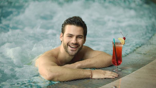 Closeup joyful man having fun in whirlpool bath. Smiling man relaxing pool spa - 写真・画像