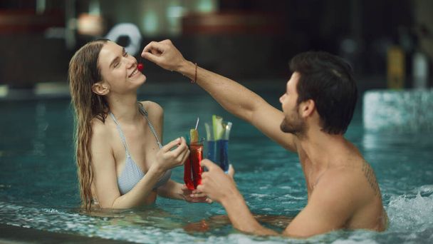 プールで楽しんでいる魅力的なカップルを閉じます。楽しいカップルドリンクカクテル - 写真・画像