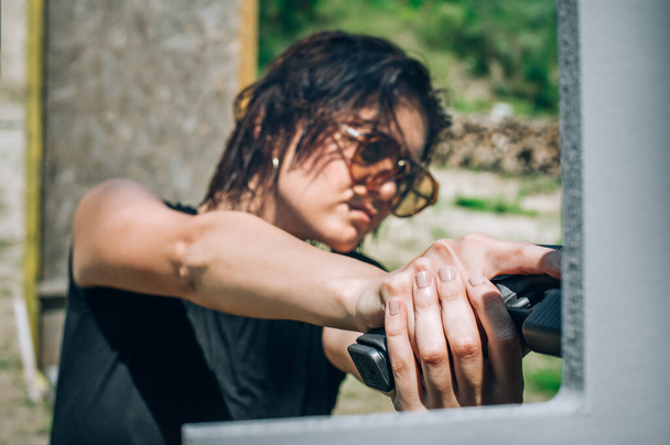 Close-up abstract view of attractive female army soldier have gun shooting training from behind and around cover or barricade. Advanced fighting tactical shooting courses on shooting range - Foto, Imagen