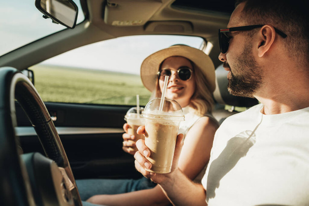 Mies ja nainen istuu autossa, juo kylmää kahvia ja nauttii seikkailusta Road Trip - Valokuva, kuva