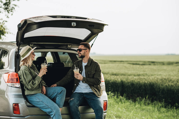 Άνδρας και γυναίκα κάθεται στο φορτηγό του αυτοκινήτου και ποτό κρύο καφέ - Φωτογραφία, εικόνα