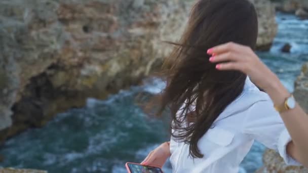 Krásná mladá žena s vlasy foukané do její tváře mořským vánkem - Záběry, video