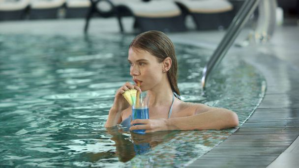 Porträt einer sexy Frau, die am Pool einen Cocktail trinkt. Nasse Mädchen ruhen sich mit Cocktail aus - Foto, Bild