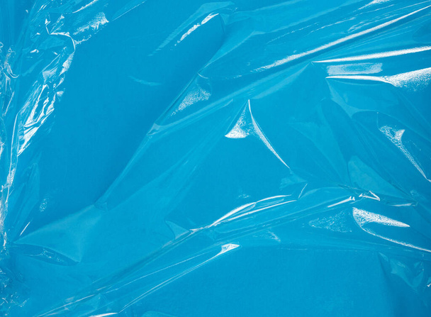 texture of a transparent stretching plastic film for packaging products on a blue background, full frame, close up - Φωτογραφία, εικόνα