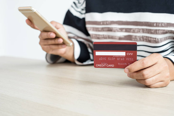 De hand van de zakenvrouw houdt een creditcard vast en gebruikt een smartphone voor online winkelen en internetbetaling op kantoor.. - Foto, afbeelding