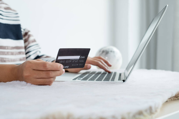 İş kadınının elinde bir kredi kartı var ve ofisteki online alışveriş ve internet ödemeleri için bir dizüstü bilgisayar kullanıyor.. - Fotoğraf, Görsel