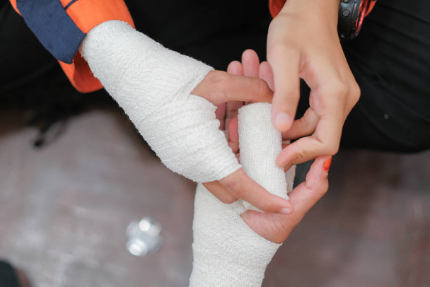 Studenckie szkolenie pierwszej pomocy w holu. Studentka próbuje wybić rękę pacjenta ze złamaną ręką z elastycznym bandażem na studiach.. - Zdjęcie, obraz