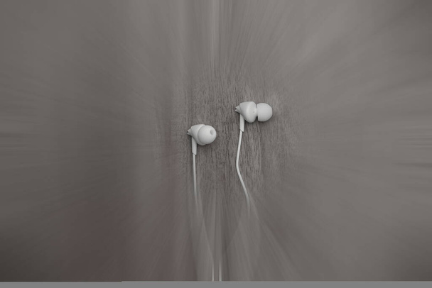 Auricular blanco con cable con fondo difuminado en movimiento aislado sobre fondo de madera. - Foto, Imagen