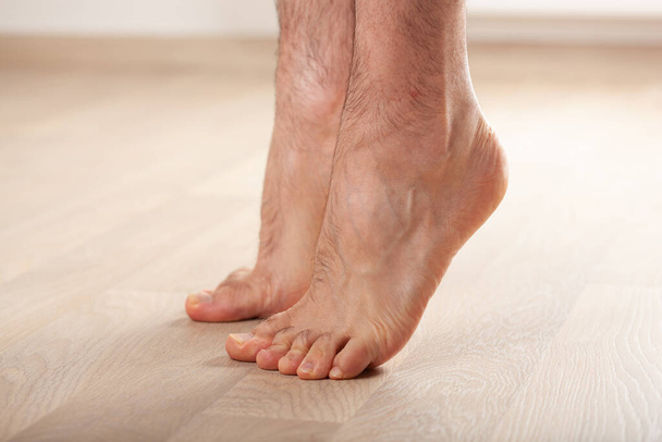 muž dělá ploché nohy korekce gymnastické cvičení stojící na nohou doma - Fotografie, Obrázek