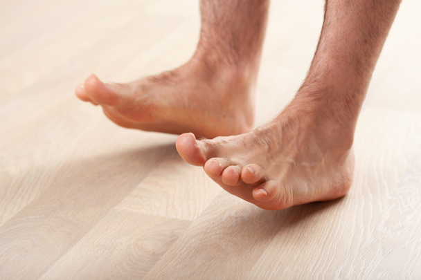 muž dělá ploché nohy korekce gymnastické cvičení stojící na podpatku doma - Fotografie, Obrázek
