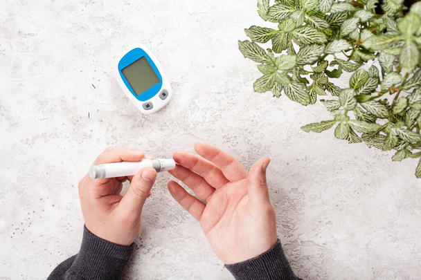 血糖値計で血糖値やケトンのレベルを確認するために、指にランセットを使用して手。糖尿病ケトダイエット｜家庭での健康管理 - 写真・画像