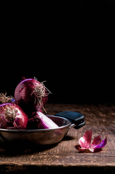Onions and half onion in a pan on a blackground close-up on wood table - Foto, immagini