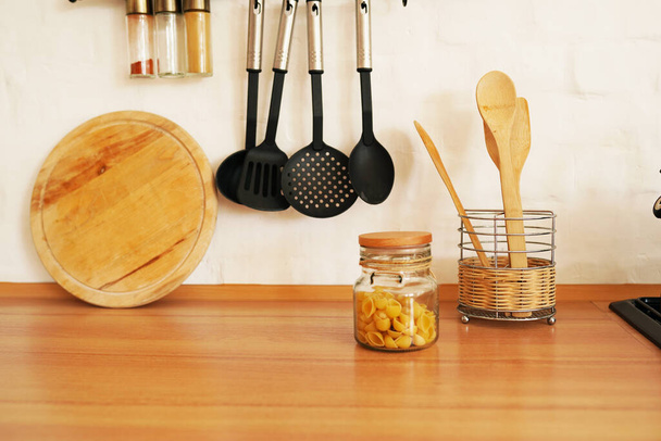 木製のテーブルの上の花瓶に木製のスプーンとキッチンウェア - 写真・画像