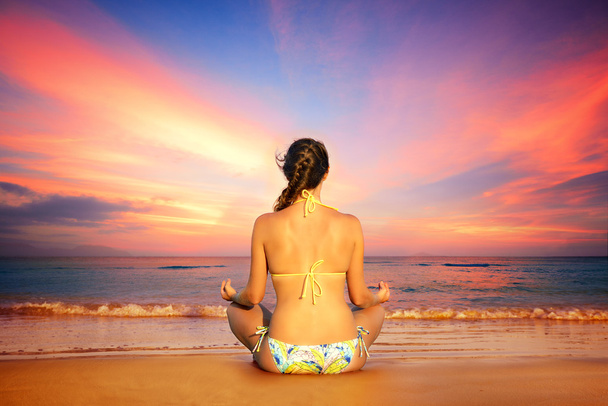 Mujer en posición de loto sobre un fondo de puesta de sol
 - Foto, Imagen