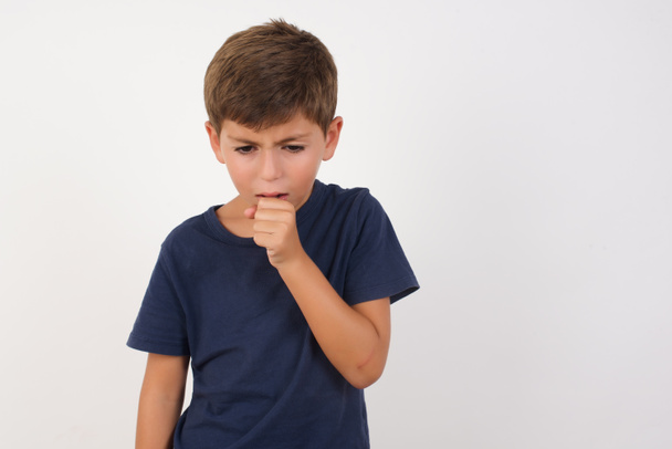 Beautiful kid boy wearing casual t-shirt standing over isolated white background, feeling unwell and coughing as symptom for cold or bronchitis. Healthcare concept. - Photo, Image