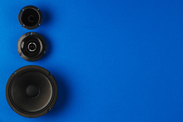Auto geluid. Auto luidsprekers, bas luidspreker en midrange luidspreker liggen op een rij op een blauwe achtergrond. Kopieerruimte - Foto, afbeelding