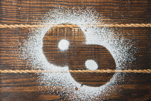 Azúcar en polvo en forma de 8 sobre un fondo de madera oscura. Concepto de Día Internacional de la Mujer. enfoque suave - Foto, Imagen