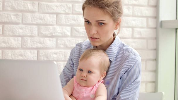 Donna concentrata con bambino che lavora sul computer portatile. Donna d'affari che lavora - Foto, immagini
