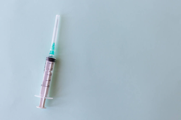 Plastic disposable syringe on light blue background alignment to the left. - Fotó, kép