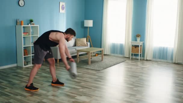 Man Is Spreading Fitness Mat and Uses Gadget - Кадри, відео