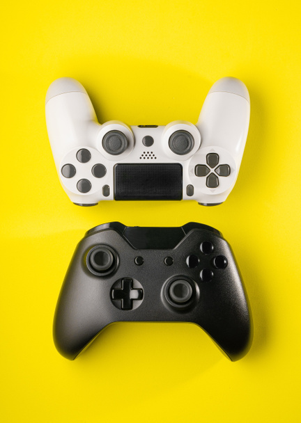Black and White game controllers on yellow background - Photo, Image