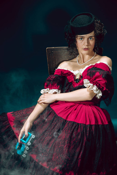 Young woman as Anna Karenina on dark blue background. Retro style, comparison of eras concept. - Foto, immagini