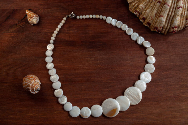 natural mother-of-pearl necklace on a wooden background - Photo, Image