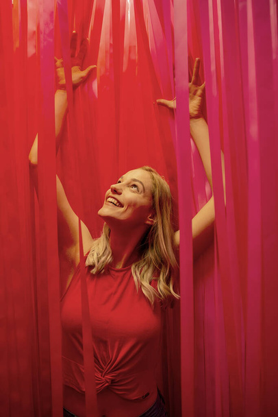 fröhliche junge Frau jubelt zwischen roten Streifen - Foto, Bild