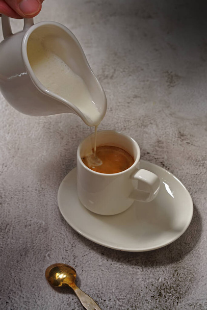 pouring milk into a cup of coffee, view from above - 写真・画像