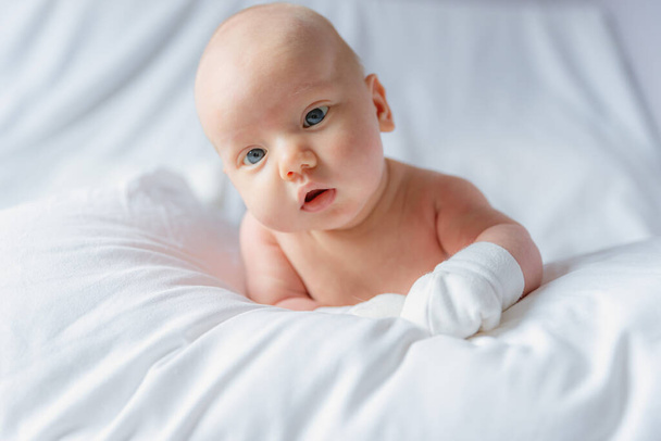 Bébé émotionnel jouant avec le regard tout en étant couché sur le lit - Photo, image