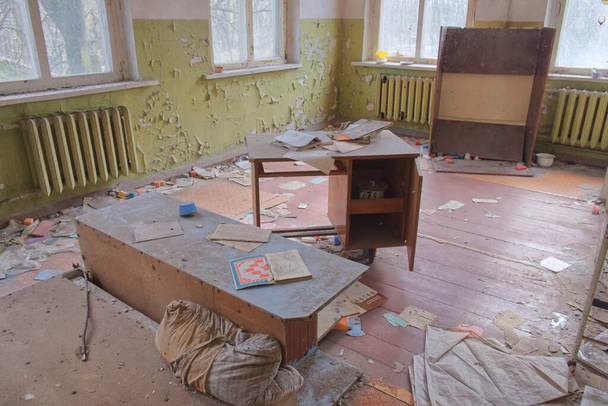 Uma sala de jardim de infância abandonada na zona de exclusão de Chernobil. Móveis antigos. Paredes esfarrapadas e um monte de lixo no chão. O interior de um edifício abandonado. - Foto, Imagem